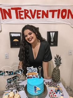 a woman standing in front of a table with a cake and cupcakes on it