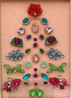 a christmas tree made out of different colored jewels and brooches in a frame