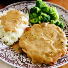 a plate with mashed potatoes, broccoli and gravy on it