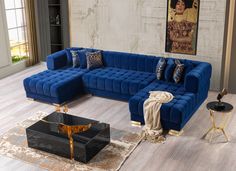 a living room with blue couches and rugs on the wooden floor, large painting in background