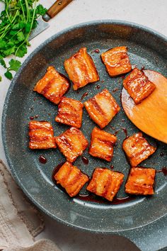 tofu being cooked in a frying pan with a wooden spoon on the side