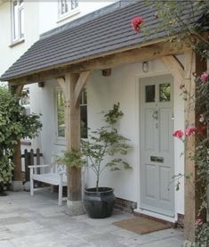 a small white house with a porch and potted plants