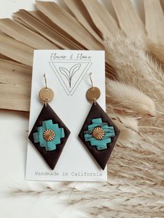 a pair of earrings sitting on top of a feather