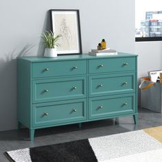 a blue dresser in a room with a potted plant next to it and a black rug on the floor