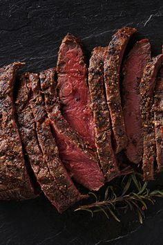 steak sliced up on a cutting board with herbs