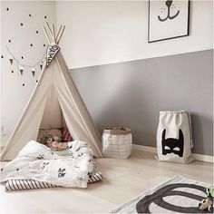 a teepee tent sitting on top of a white floor next to pillows and blankets