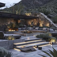 an outdoor living area with couches, fire pit and landscaping lighting up the landscape