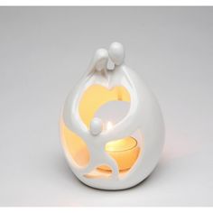 a white candle holder with an abstract design on the front and sides, lit up by a yellow light