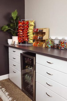 a kitchen with white cabinets and lots of candy on top of the counter next to an open refrigerator