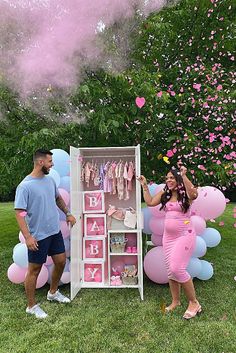 a man and woman standing in front of a baby's changing table with balloons