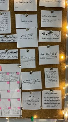 a bulletin board with notes pinned to it and lights on the wall in the background