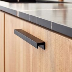 a close up of a kitchen counter with wooden cabinets and black pulls on the drawers