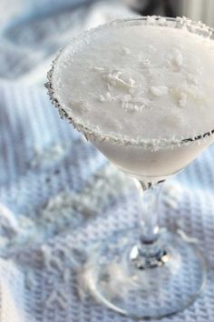 a margarita sitting on top of a table next to a glass filled with something white