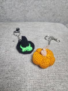 two crocheted keychains sitting on top of a gray couch next to each other