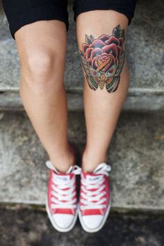 a woman's legs with tattoos on them and red shoes in front of her