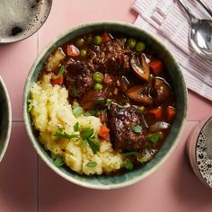 two bowls filled with meat and vegetables on top of a pink table