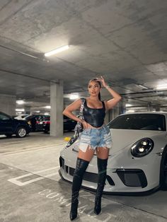 a woman standing next to a car in a parking garage