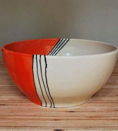 an orange and white bowl sitting on top of a wooden table