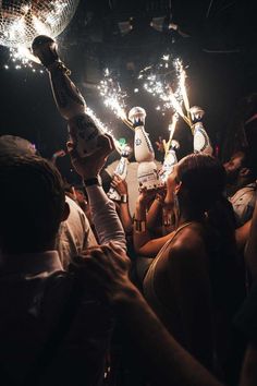 people are holding sparklers in the air at a party with disco balls and lights