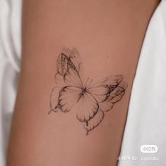 a butterfly tattoo on the back of a woman's left arm is shown in black and white