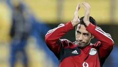 a soccer player is holding his hands up in the air while wearing a red jersey