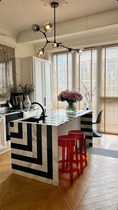 a kitchen island with two stools in front of it and a vase on the counter