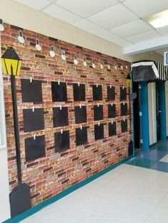 a brick wall with several pieces of black paper taped to it and hanging from the ceiling