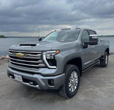 a silver truck parked in front of a body of water