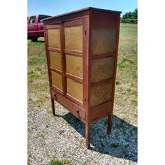 a wooden cabinet sitting in the middle of a field