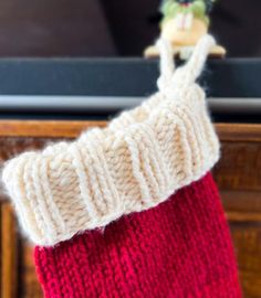 a red and white stocking hanging from a wooden pole with a television in the background