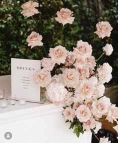 a bouquet of pink flowers sitting on top of a white table next to a card