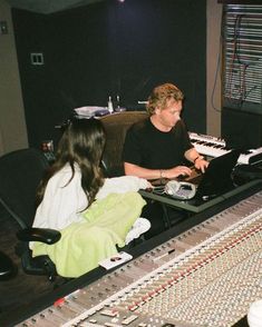 two people sitting in front of a mixing desk