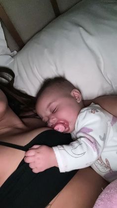 a woman laying on top of a bed holding a baby