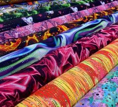 many different colored fabrics are lined up on the table together, with one being colorful and the other is bright