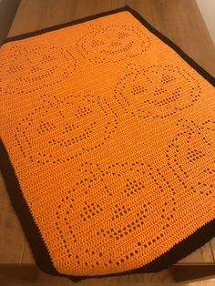 an orange crocheted blanket sitting on top of a wooden floor