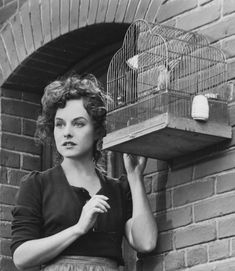 an old photo of a woman holding a bird cage