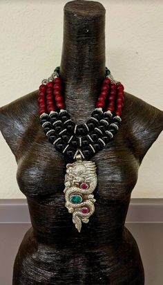 This gorgeous, high end haute couture, unisex Statement Necklace belongs in a San Francisco opera house or in a exclusive luxury Rodeo Drive boutique. A 5.5" x 2.5" Tibetan Silver Repousse Dragon Pendant inlaid with ruby and emerald is the very exotic and dramatic focal point. Pendants this large ARE Scarce and rarely come to market. But when they do, they are expensive. The heavy, triple strand, red, green and black necklace consists of black onyx, silver metal rondelles, African frosted red recycled glass, silver hematite and emerald green Czech barrel beads. This adjusts from 24" x 28" with silver tone hardware, a lobster claw clasp and a 4" extender chain. A funky 4" dangle cascades off the extender chain and down your back. From the Atelier of Kat Kouture. Luxury Red Necklace With Polished Beads, Luxury Black Beaded Necklaces, Rocker Chic Accessories, Tibetan Dragon, Haute Couture Jewelry, Unique Pendant Necklace, Statement Bib Necklace, Rodeo Drive, Chest Piece