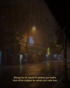 a dark city street at night with rain falling on the ground and lights in the distance