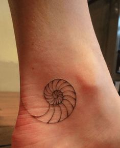 a small tattoo on the ankle of a woman's foot with a spiral design