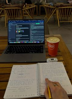 a laptop computer sitting on top of a wooden table next to a cup of coffee