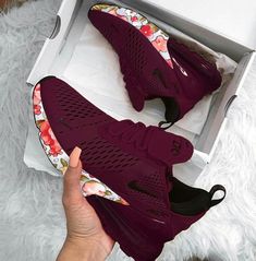 someone is holding up their maroon nike shoes in a box on a white fur rug