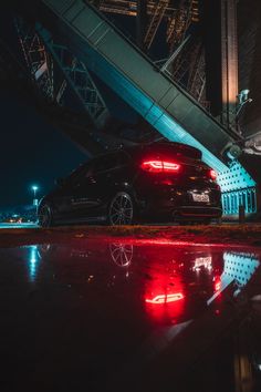 a black car parked under a bridge at night