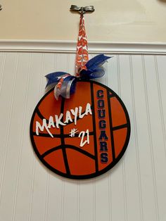 a basketball hanging on the wall with a ribbon around it's neck and name