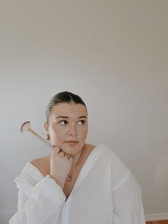 a woman in white shirt holding a golf club and looking at the camera with serious look on her face