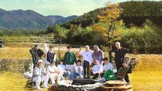 a group of people posing for a photo in front of some hills and trees with mountains behind them