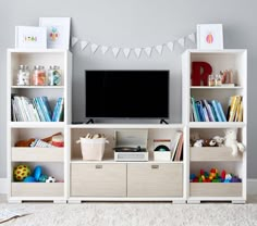 a living room with white shelving units and a flat screen tv