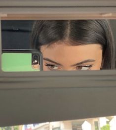 a woman looking at her cell phone through the window