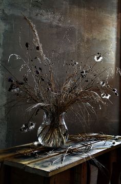 a vase filled with dried flowers on top of a wooden table