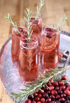 three glasses filled with wine and garnished with rosemary sprigs on a tray