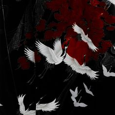 several white birds flying in the air near red and black flowers on a black background